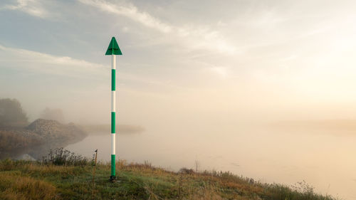 Road sign on landscape against sky