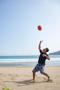 Full length of woman jumping on beach against sky