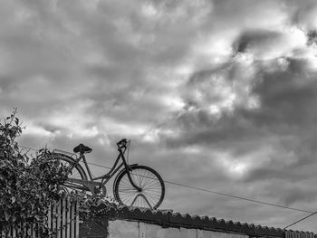 Low angle view of bicycle against cloudy sky