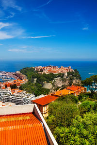 High angle view of townscape by sea against blue sky