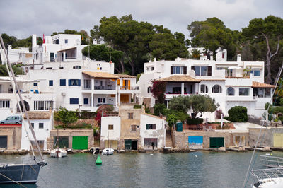 Sailboats in sea by townscape against sky, cala d'or 