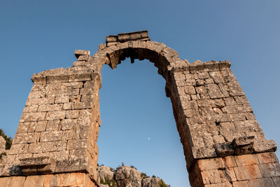 Low angle view of old ruins against clear blue sky