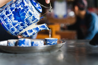 Midsection of woman pouring drink in bowl on table