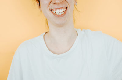 Portrait of young woman standing against yellow background