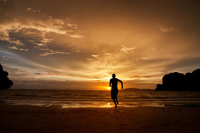 Silhouette man on beach against sky during sunset