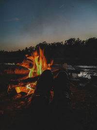 Low section of people relaxing on log at night