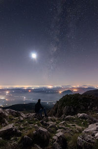 Rear view of woman looking at rocks against sky at night