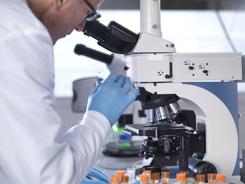 Side view of scientist analyzing blood samples through microscope in laboratory