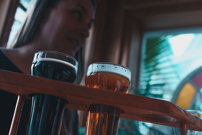 Low angle view of craft beer with woman in background at bar