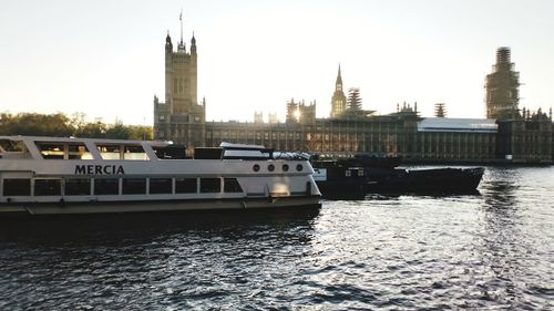 Boats in river against buildings in city