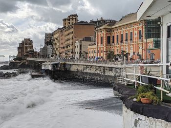 Bridge over canal by buildings in city against sky