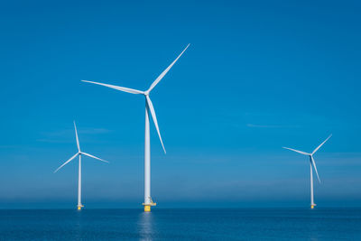 Low angle view of windmill against clear blue sky