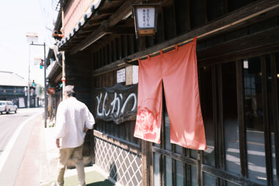 Rear view of men walking on street amidst buildings