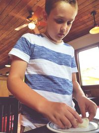 Low angle view of boy kneading dough at table