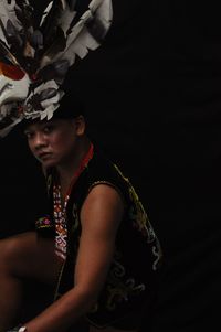 Woman looking away while standing against black background