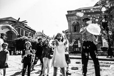 People walking on street in city against sky