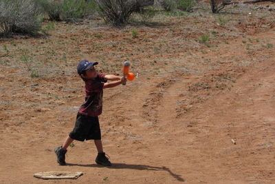 Full length of boy playing baseball on field