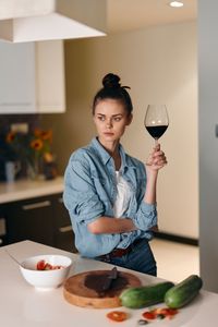 Portrait of young woman holding wineglass on table