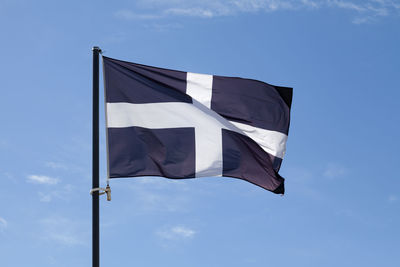 Saint piran's flag - cornwall - waving atop of its pole against a blue sky.