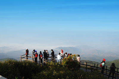 High angle view of people standing at observation point by mountains against sky in foggy weather