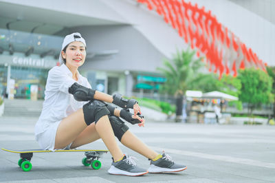 Portrait of woman sitting on skateboard