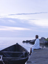 Rear view of man standing on sea against sky