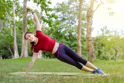 Full length of woman with arms raised against trees