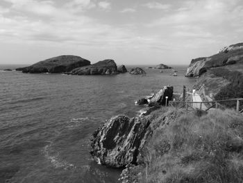 Scenic view of sea by cliff against sky