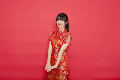 Woman with umbrella standing against red background