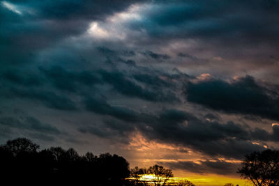 Low angle view of silhouette trees against dramatic sky