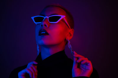 Close-up of woman wearing sunglasses against black background