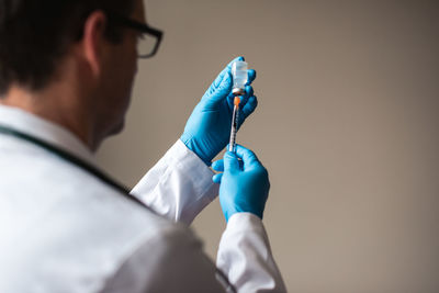 Doctor in white coat drawing vaccine into a syringe for injection.