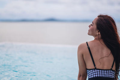 Rear view of woman standing at beach