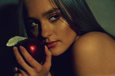 Close-up of young woman holding artificial shiny apple