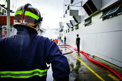 Rear view of firefighter walking on wet footpath