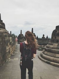 Rear view of woman with tousled hair standing by monument