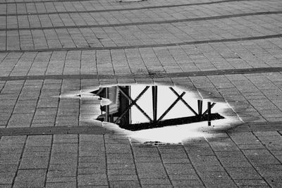 Built structure reflecting on puddle over cobbled street