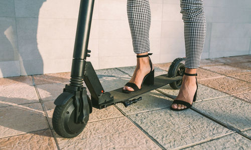 Low section of businesswoman riding electric push scooter on sidewalk