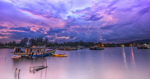 Boats in sea against cloudy sky