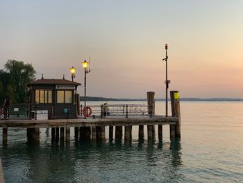 Pier on sea against sky at sunset