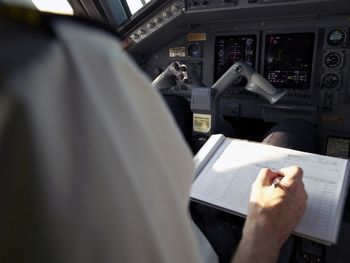 Pilot writing and checking in logbook