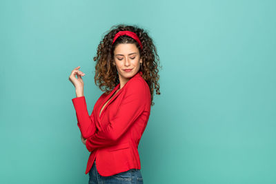 Young woman standing against blue wall