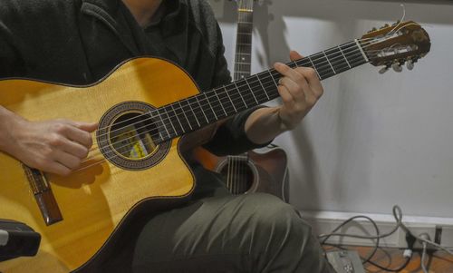 Midsection of man playing guitar