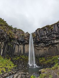 Scenic view of waterfall against sky
