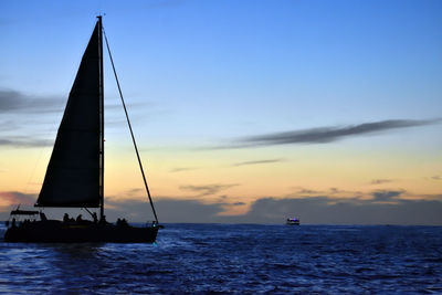 Silhouette sailboat sailing on sea against sky during sunset