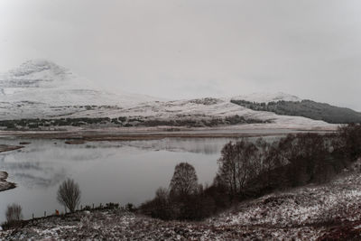 Scenic view of lake by snowcapped mountain against sky