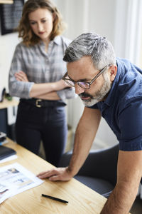 Businessman discussing with female colleague at desk in creative office