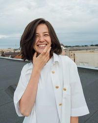 Brunette with short hair woman wearing all white on a roof portrait smiling 