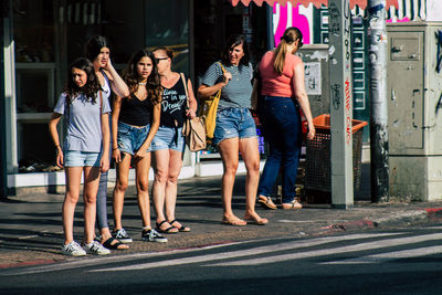 Full length of friends standing on road in city