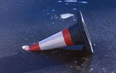 A traffic cone on a solid sheet of ice in the sun